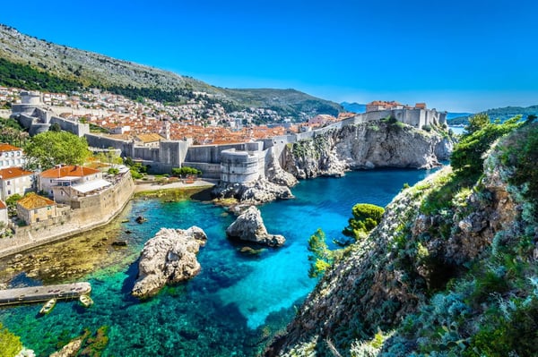 A scenic image of Dubrovnik, Croatia, highlighting its ancient city walls, iconic red-roofed buildings and beautiful Adriatic coastline.